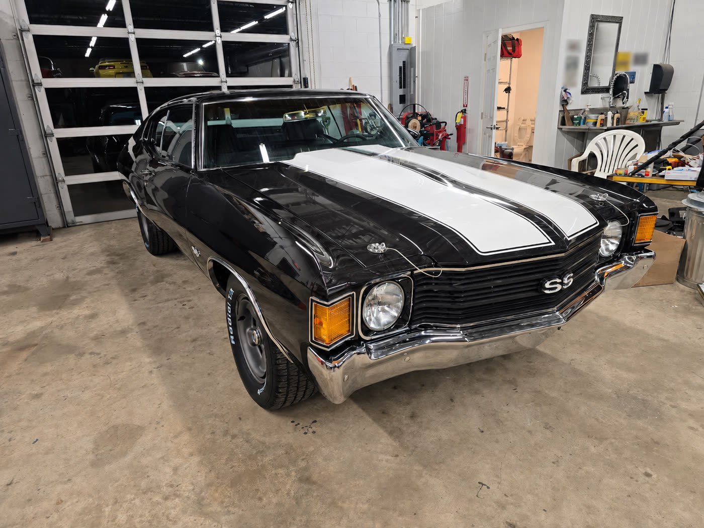 Finished black Chevrolet Chevelle with white racing stripes after paint refinishing